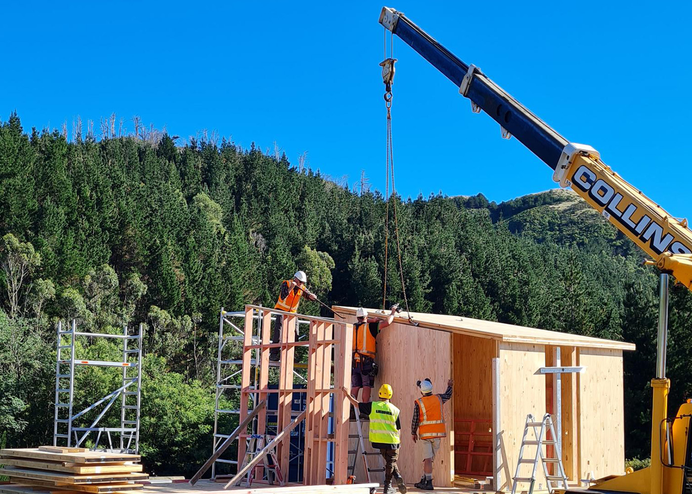 Builders guide panel being placed by crane for modular Te Whare-iti home.