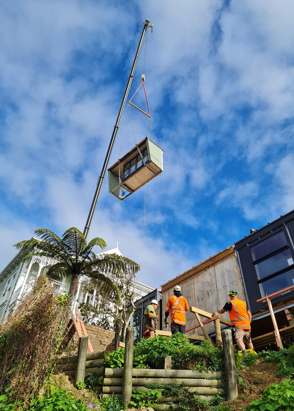 Building team watch as crane lowers Te Whare-iti module into place on customer's site.