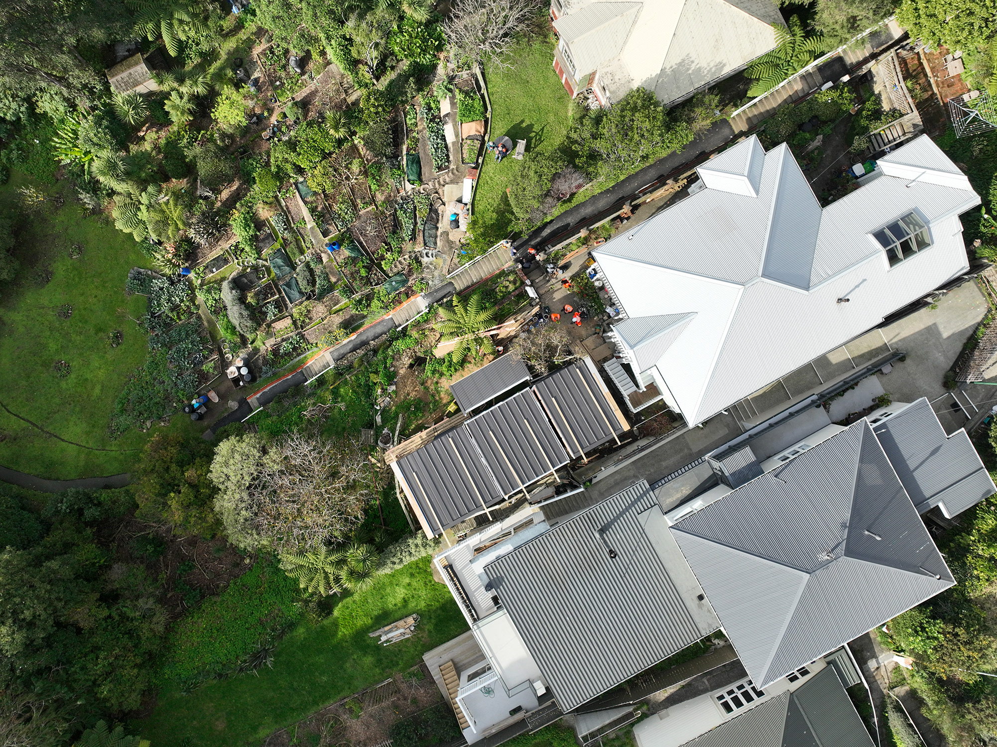 Arial view of completed Te Whare-iti modular house on the left, and the white-roofed house that the modules were craned over. 